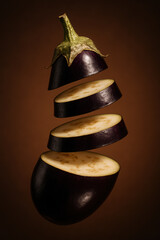 flying sliced eggplant on brown background in vertical close-up. side view. autumn vegetable concept
