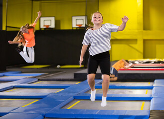 Playful girl jumping on trampoline at playground indoor