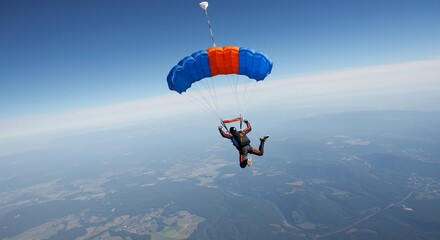A skydiver in freefall with a blue and orange parachute against a clear blue sky background view
