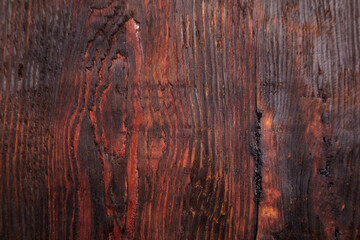 Detailed close-up view of a dark brown wooden surface with pronounced grain patterns, natural...
