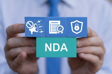 Fototapeta na wymiar Doctor holding colorful blocks with icons sees abbreviation: NDA. NDA or Non disclosure agreement contract concept. Legal acknowledge signing of confidential NDA document.