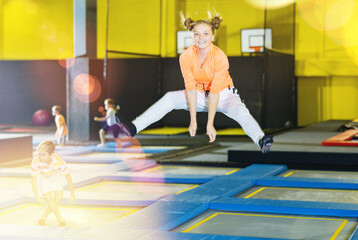 Obraz premium Playful girl jumping on trampoline at playground indoor