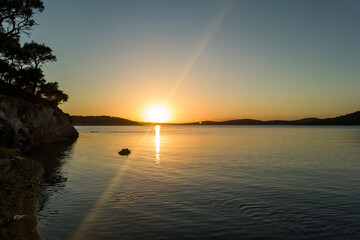 Idyllic Sunset Over Serene Sea with Rocky Coastline and Pine Trees. Tranquil Nature Landscape, Golden Hour, Calm Water, Peaceful Scenery, Travel Destination, Coastal View, Summer Evening Vibes