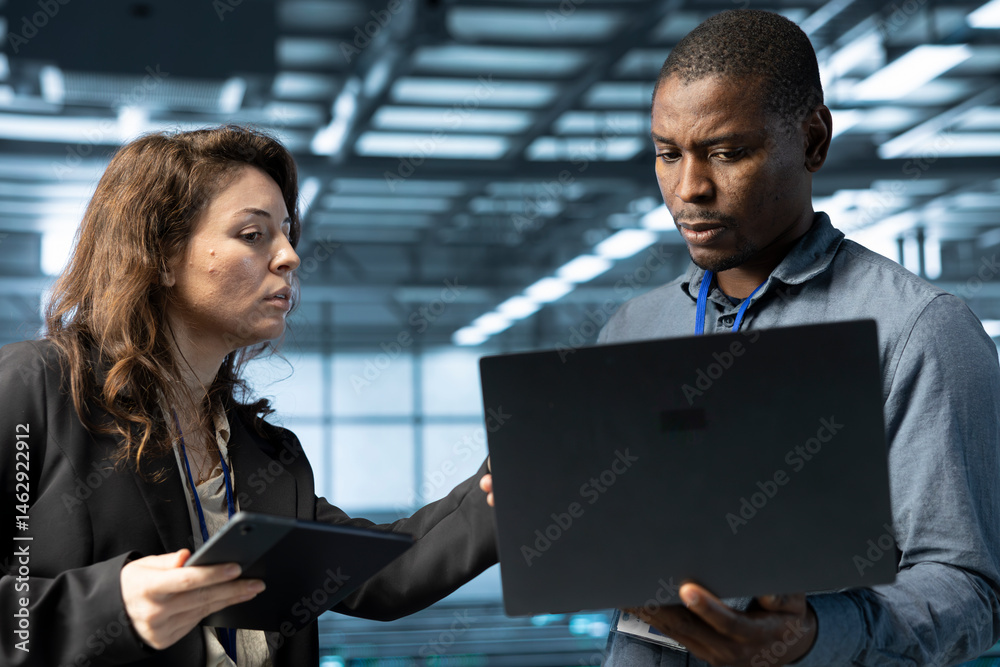 Poster system administrators using laptop in data center, managing server virtualization. it specialists us