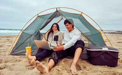 Young couple enjoying beach camping with technology
