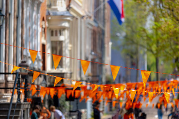 Colourful of King’s Day (in Dutch: Koningsdag) Selective focus of pennant orange flags hanging...