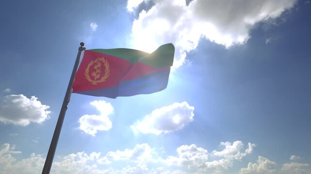 Eritrea Flag waving on a Flagpole from a Moving Angle in front of a blue sky with clouds	