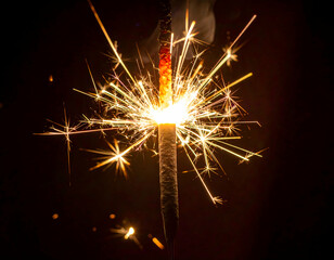 Sparkler igniting in darkness, creating bright sparks and festive atmosphere for celebrations