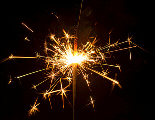 Sparkler illuminating the night sky, creating vibrant sparks, with a dark background enhancing the glow