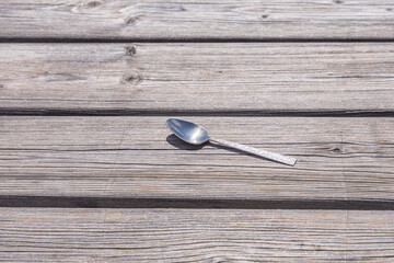 One metal spoon is on the gray wooden background