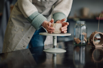 Ceramist molding clay on pottery wheel in workshop