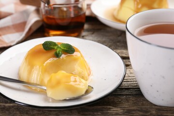 Delicious pudding with caramel sauce and mint served on wooden table, closeup