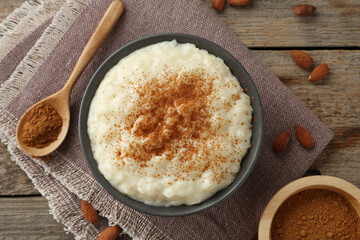 Delicious rice pudding with cinnamon and almonds on wooden table, flat lay