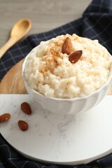 Delicious rice pudding with cinnamon, almonds and spoon on table, closeup