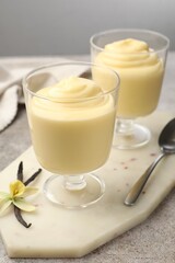 Tasty vanilla pudding, pods and flower on grey table, closeup