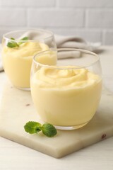 Tasty vanilla pudding with mint on white wooden table, closeup