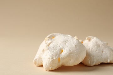 Delicious homemade meringue cookies on beige background, closeup. Space for text