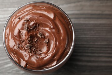Delicious chocolate pudding in glass on wooden table, top view. Space for text