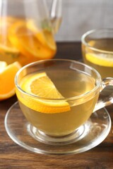 Aromatic fruit tea with orange on wooden table, closeup