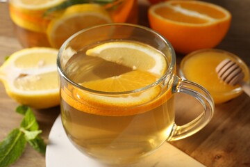 Aromatic fruit tea in glass cup, orange, lemon, honey and mint on wooden table, closeup