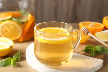 Aromatic fruit tea in glass cup, orange, lemon, honey and mint on wooden table, closeup
