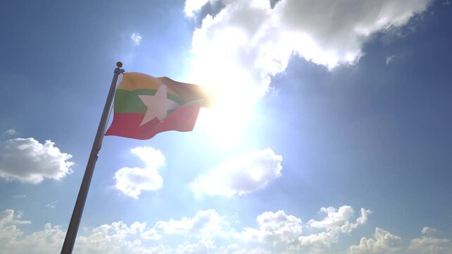 Myanmar Flag waving on a Flagpole from a Moving Angle in front of a blue sky with clouds	