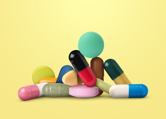 Many different antibiotic pills on yellow background