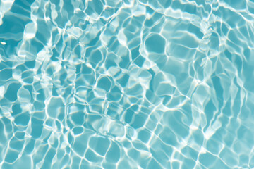 Blue water with ripples on the surface. Defocus blurred transparent blue colored clear calm water surface texture with splashes and bubbles. Water waves with shining pattern texture background.