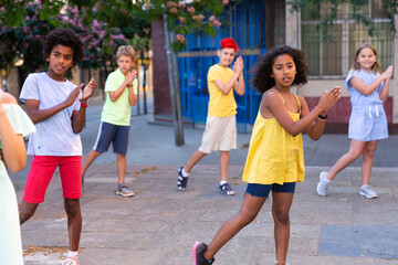 Children exercising contemporary dance moves during their outdoor rehearsal.