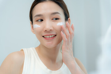 Beautiful Asian woman smile use cream for good skin. face of a healthy woman apply cream and makeup. Advertisement for skin cream, anti-wrinkle, baby face, whitening, moisturizer, tighten pores serum