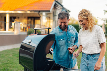 Couple grilling meat and having fun in backyard of house