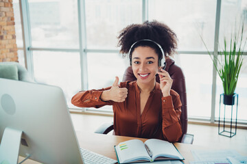 Professional businesswoman wearing a headset, working in an office with modern furnishings and...