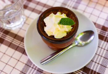 Delicate flan dessert made of milk, sugar and eggs is served in miniature bowl. Dish is decorated with leaf of fragrant fresh mint