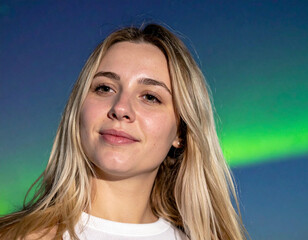 Portrait of Young Woman with Long Blonde Hair Against Blue and Green Aurora Sky
