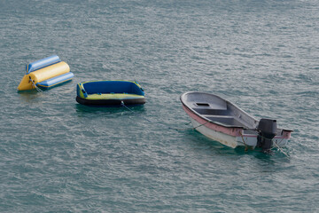 Small Boat and Inflatable Banana Boat floating in Ocean Water.