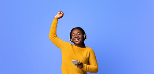 Listen Music Online. Carefree Black Woman With Wireless Headphones And Smartphone Dancing With...