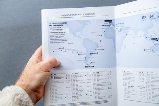 Paris, France - Mar 10, 2025: A hand holds open a cruise brochure displaying the MSC Magnifica 2025 world cruise route map and detailed itinerary covering ports 