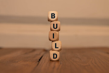 The word BUILD is written on a wooden box, miniature people