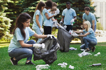 Volunteers picking up litter in dirty summer park. Ecology and environmentalism concept, copy space