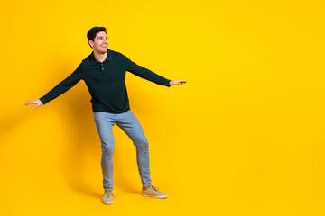 Young man in a stylish green shirt posing joyfully against a vibrant yellow background, showcasing a cheerful and modern lifestyle