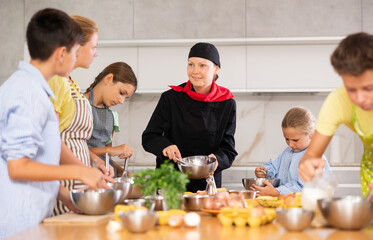 Team of teenagers and female chef at cooking classes. Learn to beat raw eggs