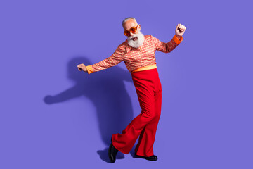 Stylish elderly man dancing joyfully in retro-inspired outfit with vibrant red pants and vintage...