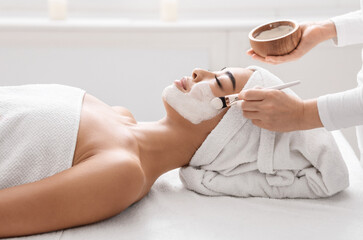 Skin Lifting Treatment. Young asian woman getting facial nourishing mask by professional beautician at spa salon, calm lady enjoying wellness day and beauty procedures, side view with copy space