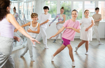 Young girls and boys repeat the movements of dance teacher, training in a spacious studio