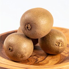 Ripe chico fruits with sandy brown skin and caramel-colored flesh on hand-carved wooden plate isolated background, full depth of field