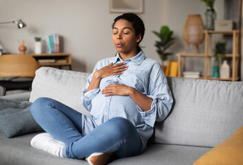 Pregnancy Yoga. Pregnant African American Woman Doing Breathing Exercise With Eyes Closed Relaxing...