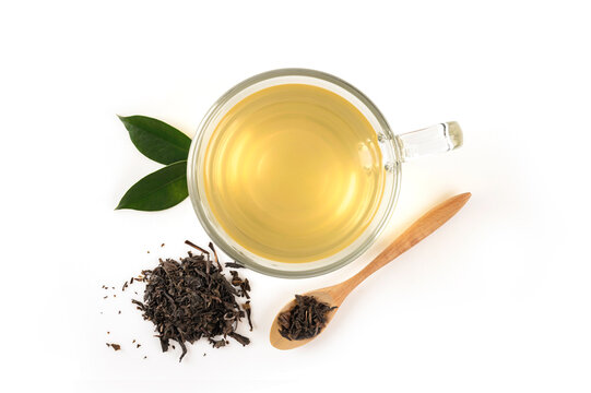 Cup of hot black tea with dry tea and leaves isolates on white background. Top view