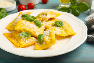 Delicious ravioli with cheese and basil on light blue wooden table, closeup