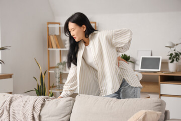 Beautiful young Asian woman suffering from back pain at home