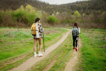 Obraz premium Two female friends hike or trek through scenic nature with hiking sticks and gear